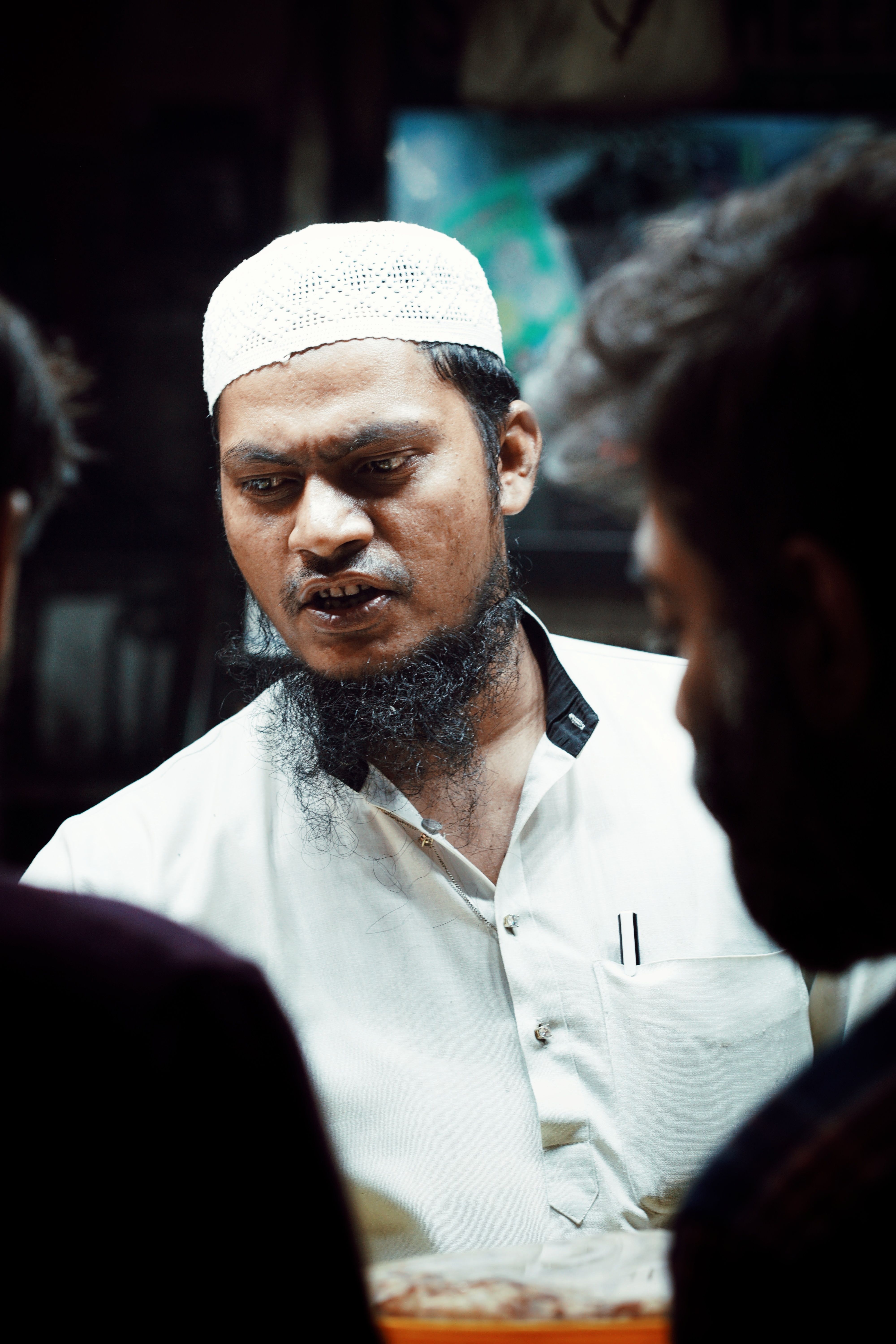 A portrait of a bearded man wearing traditional attire, captured in an indoor setting in India.