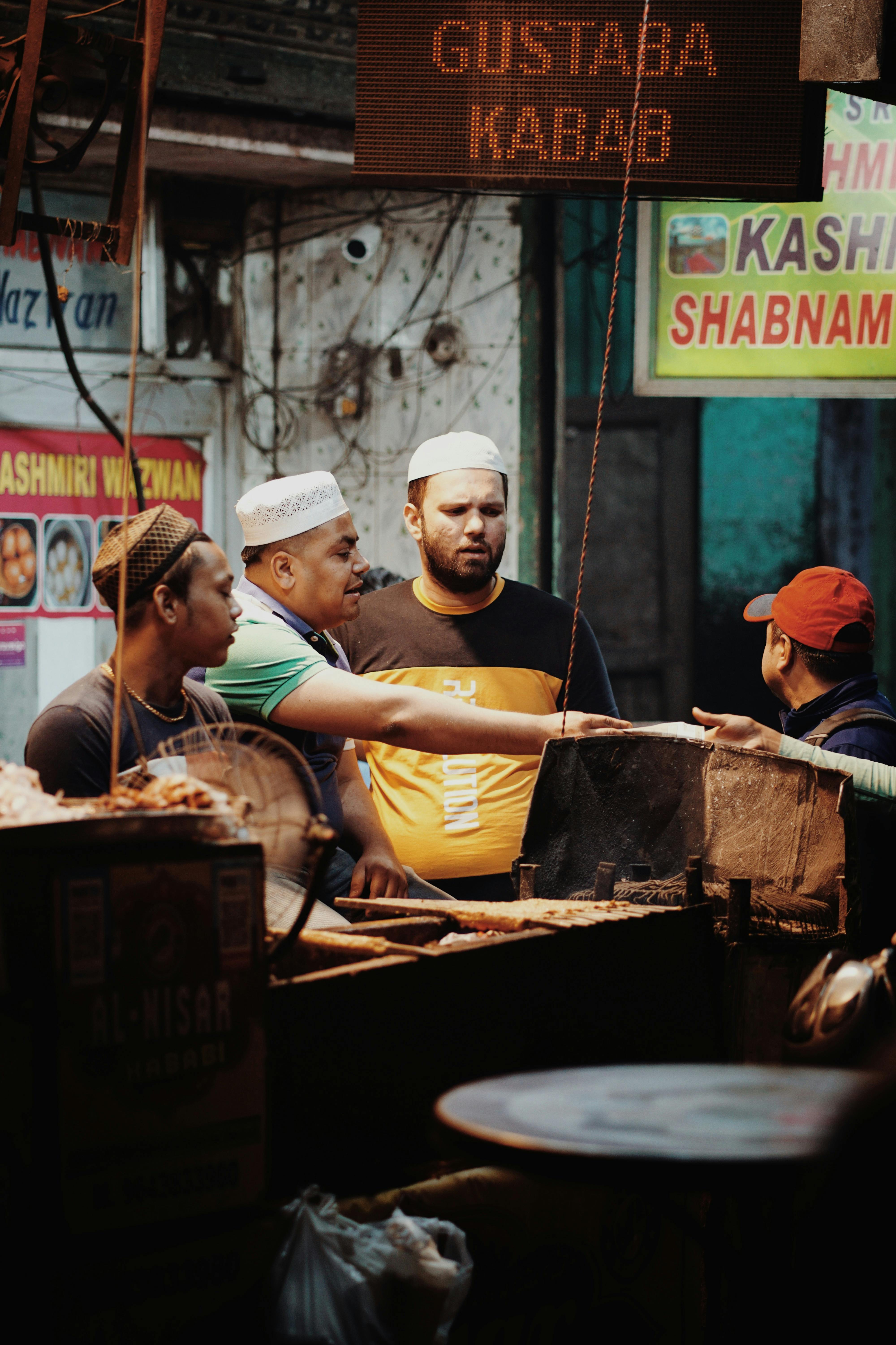 Street food vendors interacting with customers at a busy night market in Delhi, India.