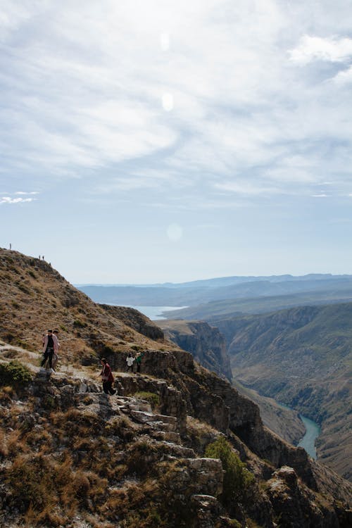 People Hiking on Hills over River in Valley