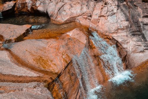 Free Experience the tranquility of a cascading waterfall over rugged rocks in a serene natural environment. Stock Photo