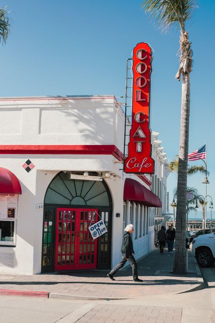 A lively street view of Cool Cat Cafe with palm trees and blue skies in Pismo Beach.