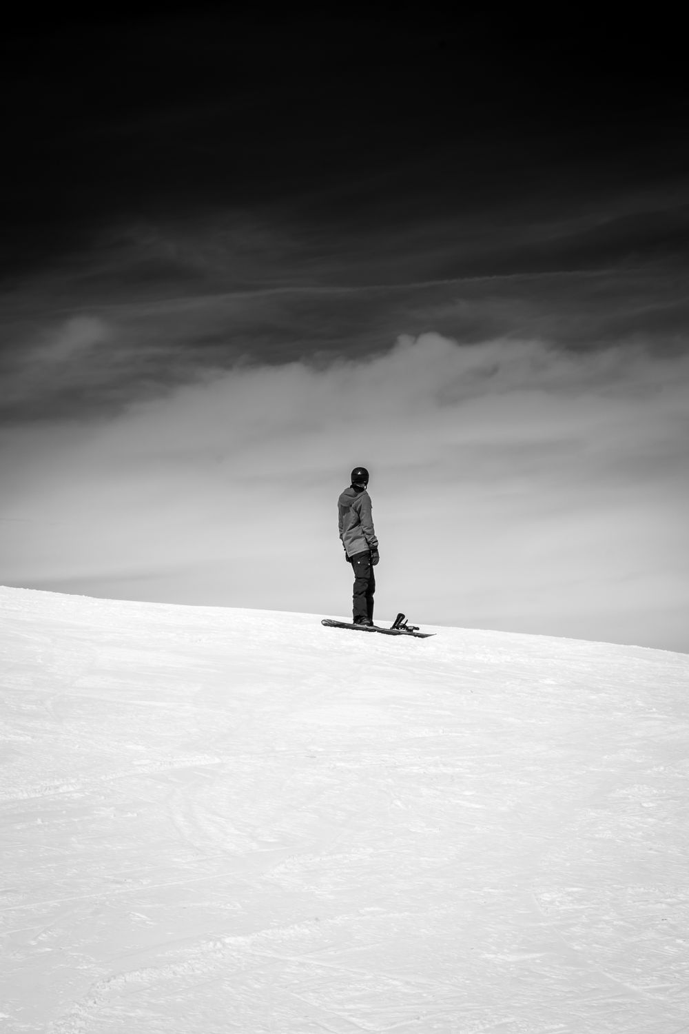 A lone snowboarder standing on an open snowfield, photo by Chris F on Pexels