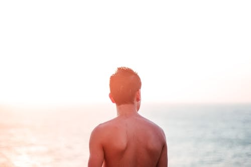 Topless Man Standing At Seashore
