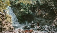 一个人站在绿石景观前欣赏瀑布，完美的旅行灵感