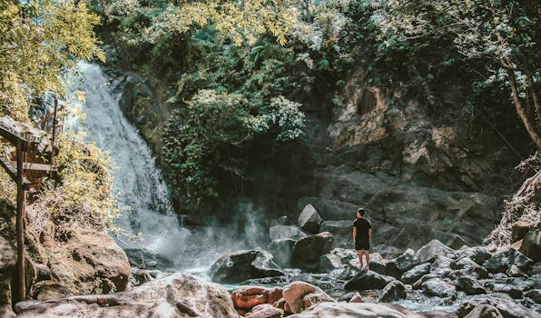 一个人站在绿石景观前欣赏瀑布，完美的旅行灵感