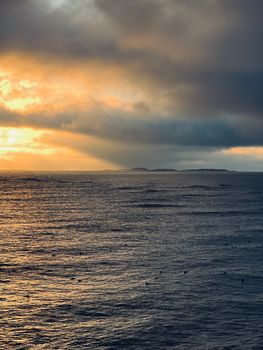 A stunning ocean view at sunset with dramatic clouds, creating a serene atmosphere.