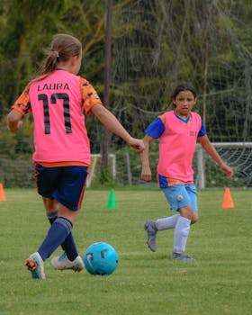 Two teenage girls engaging in a lively soccer match on an outdoor field.
