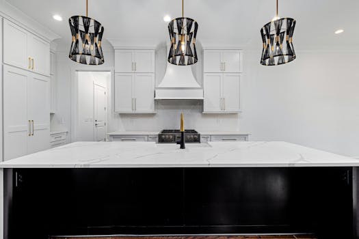 Sleek modern kitchen featuring white cabinets, a large island, and pendant lighting.