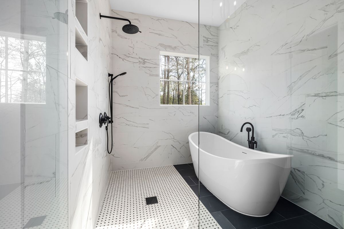 Airy Hamptons bathroom with white marble tiles and a freestanding tub