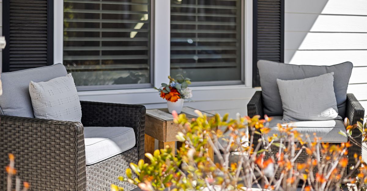 Outdoor patio scene featuring wicker armchairs and plants in vibrant sunlight.