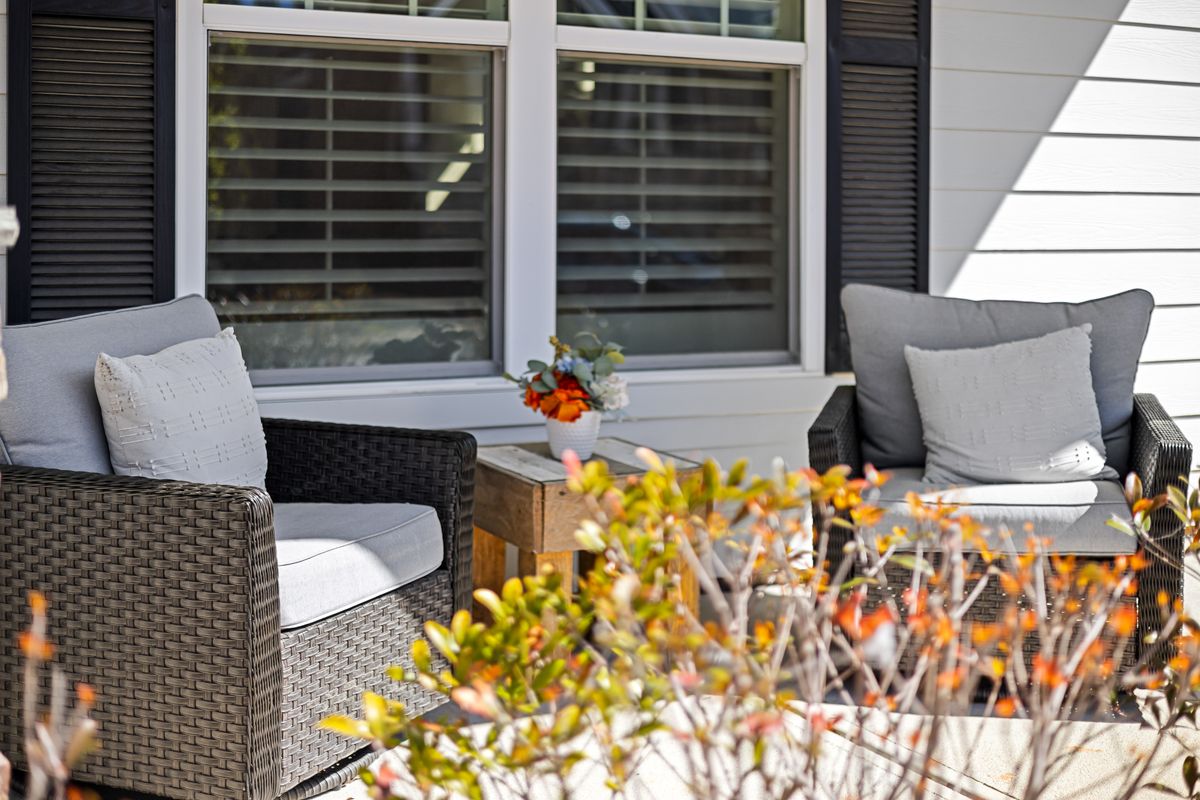 Outdoor patio scene featuring wicker armchairs and plants in vibrant sunlight. Stock Photo.