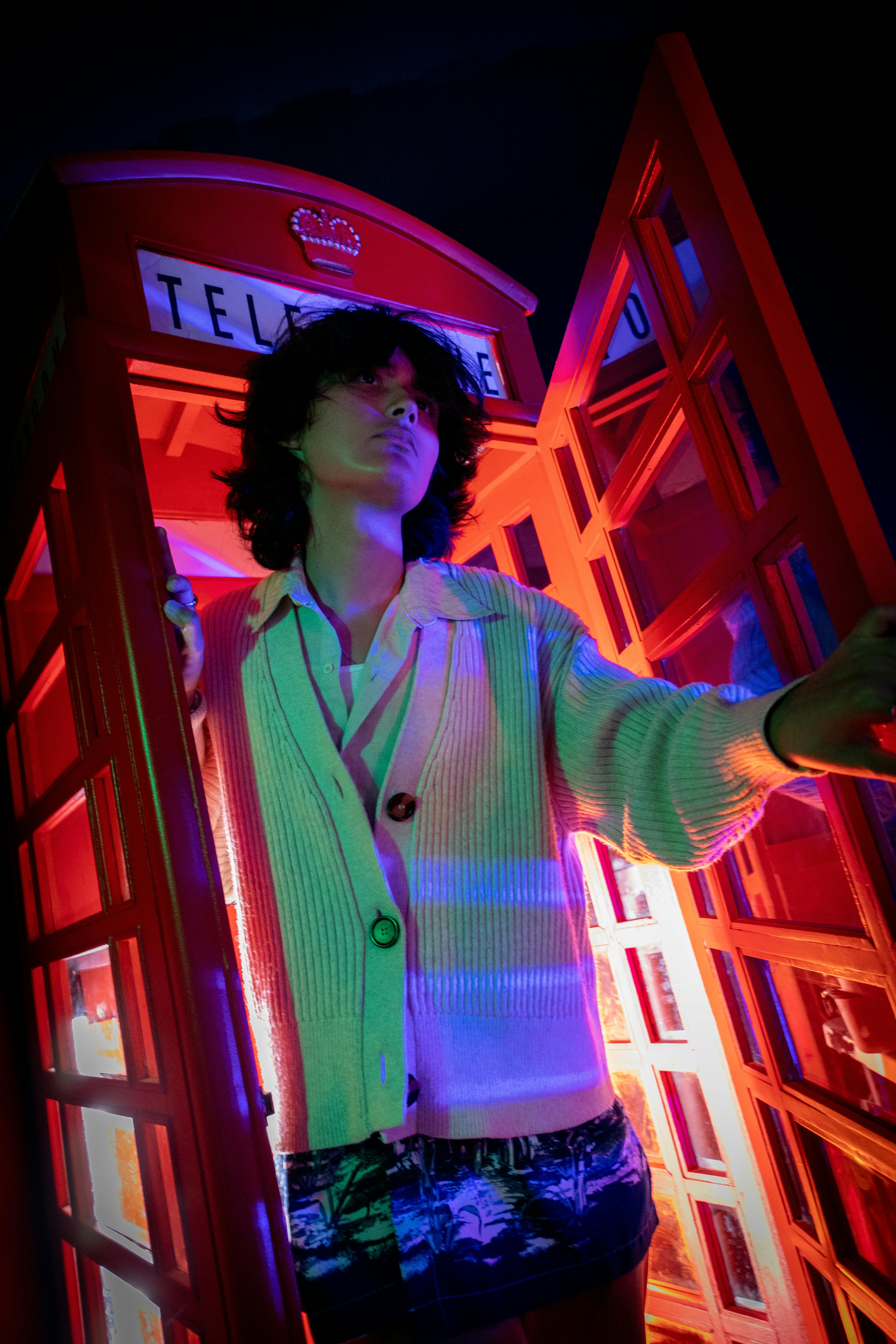 a woman standing in a red telephone booth