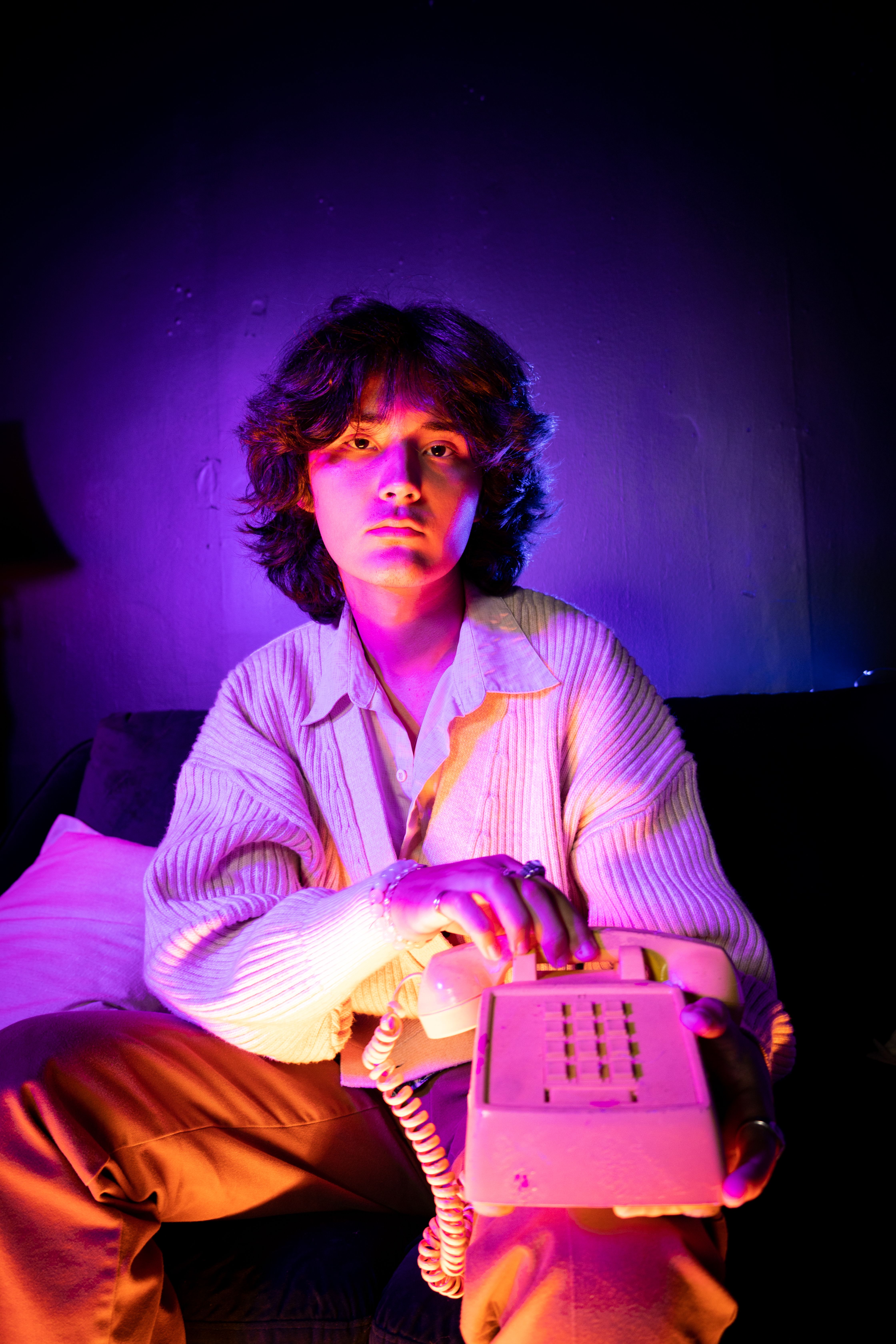 A dramatic portrait featuring a person holding a vintage telephone under colorful lighting.