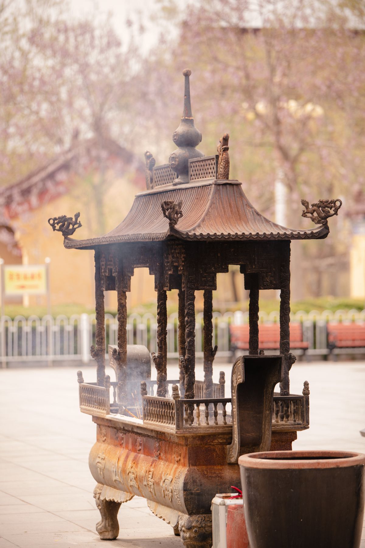 A traditional incense burner releasing fragrant smoke at a Buddhist temple