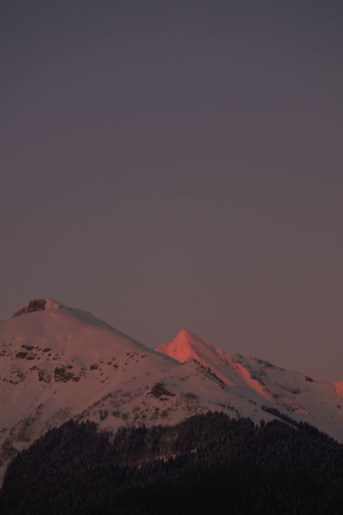 Free Scenic view of snowcapped mountains during dusk with a pink and purple sky, creating a serene atmosphere. Stock Photo