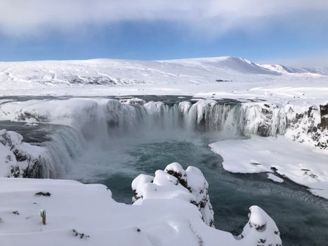 Snow-covered Godafoss waterfall in Iceland offers a breathtaking winter view.