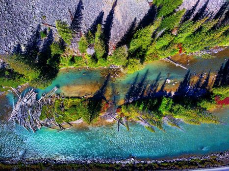 Breathtaking aerial view of a vibrant river and lush forest in Gallatin Gateway, Montana.