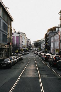 View of a bustling city street with parked cars and urban buildings on both sides.