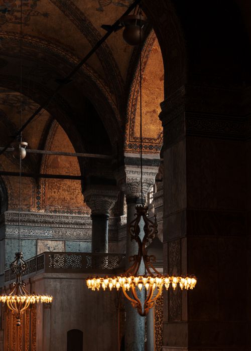 Free Elegant chandeliers illuminate the historic arches and columns of Hagia Sophia in Istanbul. Stock Photo