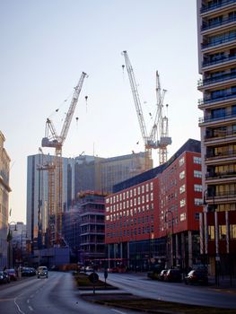 Cityscape of Berlin with construction cranes and modern buildings under a clear sky.