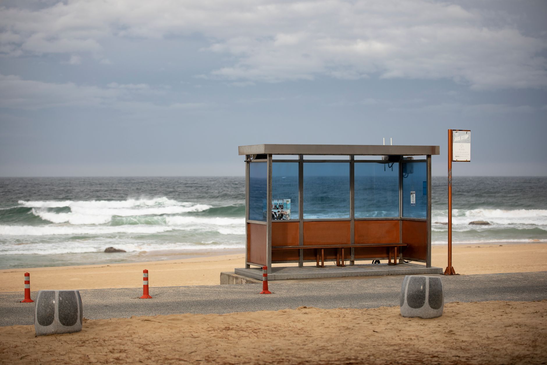 A solitary bus stop by the sea on a cloudy day in Gangneung-si, South Korea.