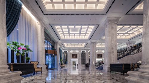 Free Elegant hotel lobby featuring grand marble columns, high ceiling, and decorative elements in a sophisticated design. Stock Photo