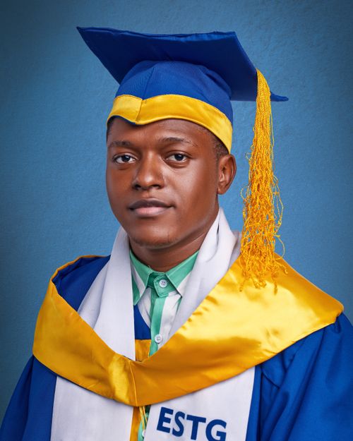 Free A portrait of a young graduate wearing a cap and gown against a blue background. Stock Photo