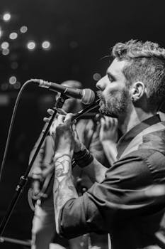 Monochrome image of a male musician playing flute at a concert.