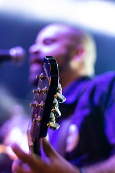 Dynamic close-up shot of a guitarist performing live, showcasing the guitar's tuning pegs during a concert.