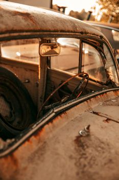 Close-up of a rusty vintage car interior, highlighting decay and nostalgia at sunset.