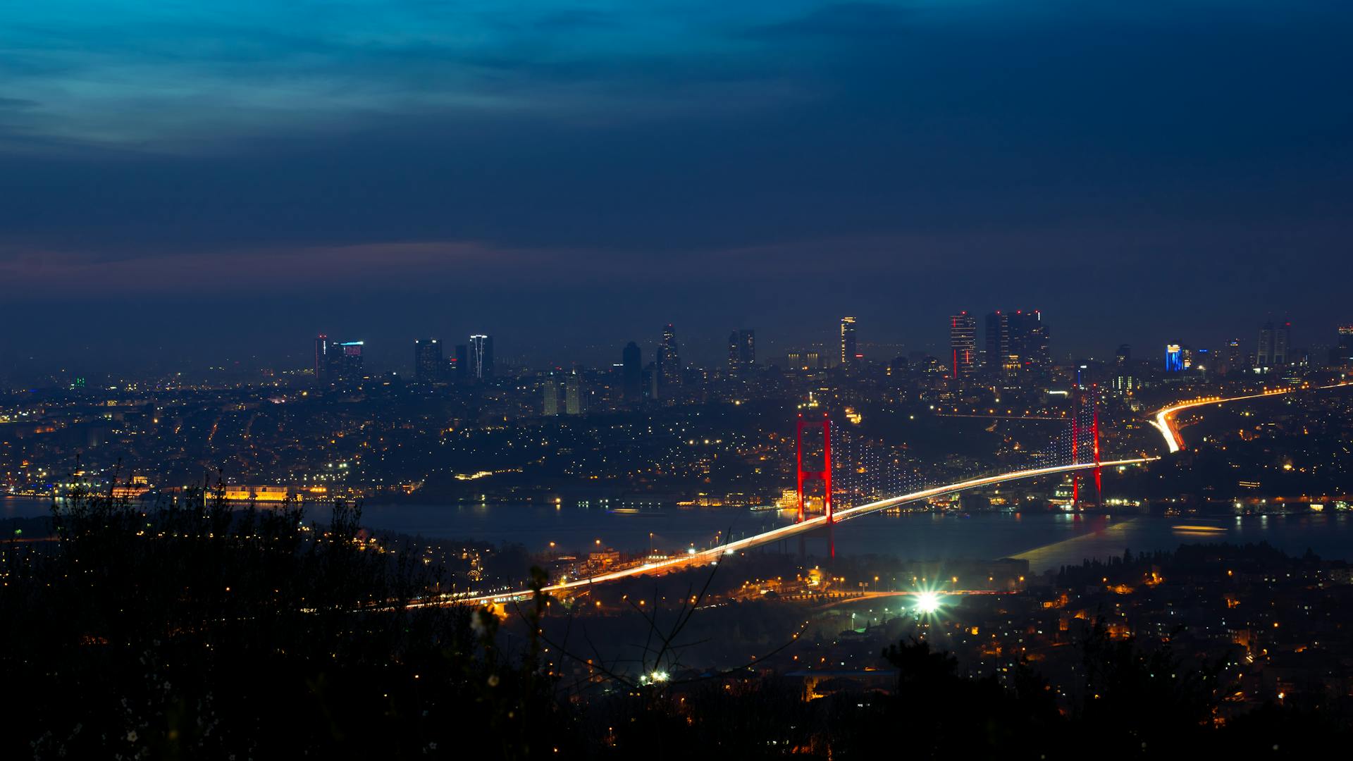 Illuminated Bosphorus Bridge and Istanbul cityscape captured at night creating a breathtaking urban scene.