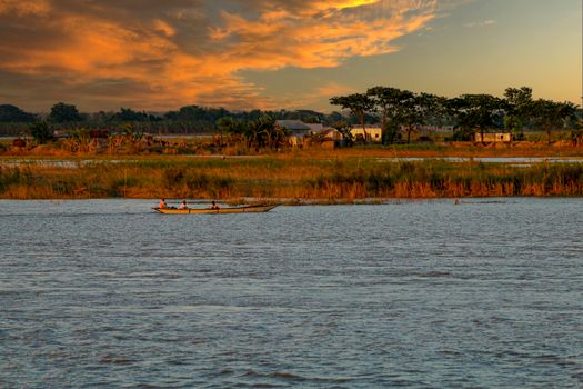 A serene boat ride during sunset on a calm river in Faridpur, Bangladesh.