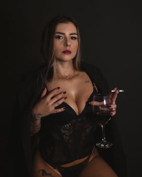 Confident woman in sensual lingerie with wineglass and cigarette, exuding elegance.