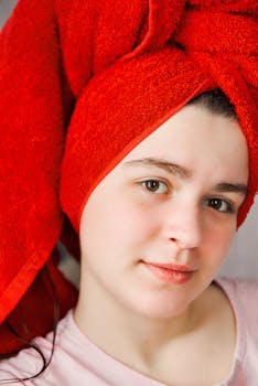 Portrait of a young woman with a vibrant red towel wrapped around her head, giving a fresh and natural look.