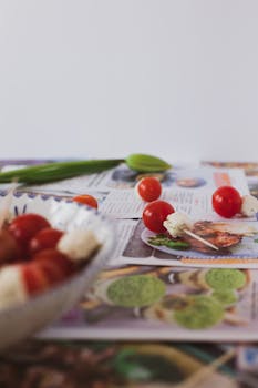 Cherry tomatoes and cheese on cook book pages, perfect for recipe creations.