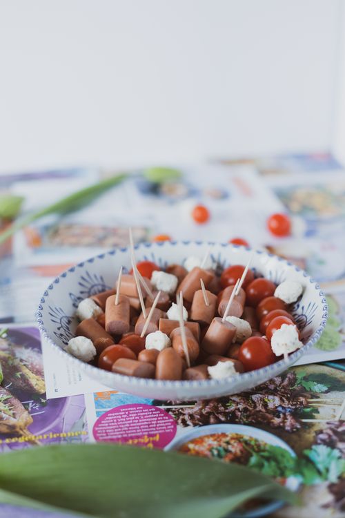Free Delicious platter of mini sausages, cherry tomatoes, and cheese skewers on a decorated table. Stock Photo