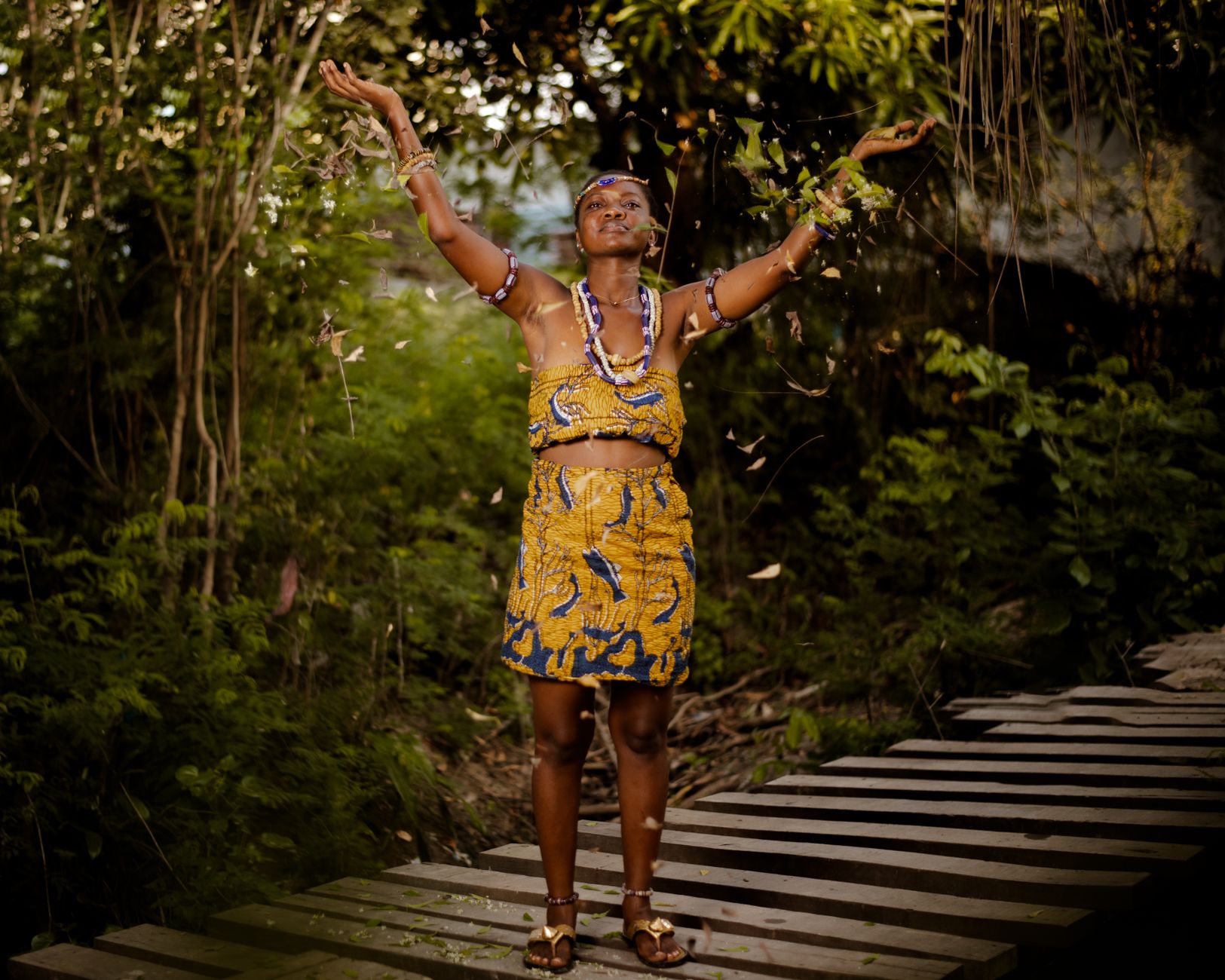 A woman in traditional clothing participating in an outdoor tribal ritual.