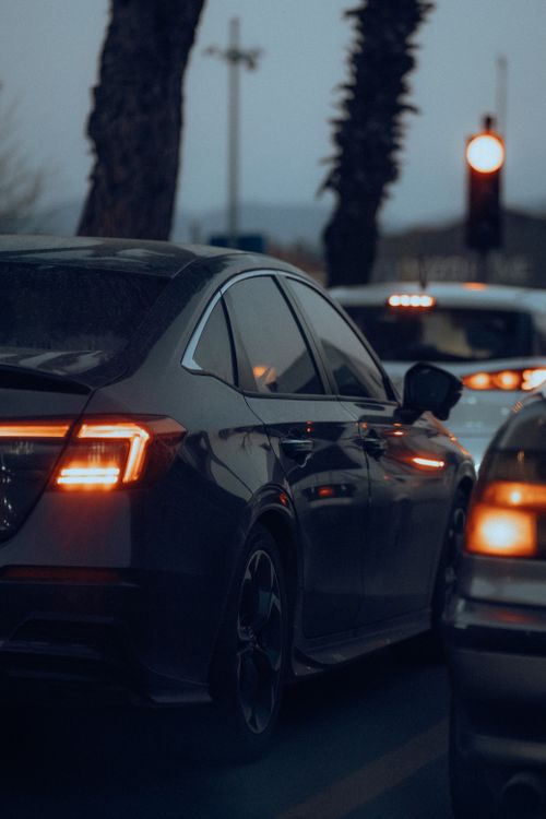 Free View of cars stuck in evening city traffic with red lights glowing, creating a moody urban scene. Stock Photo