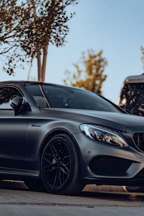 Free A modern, metallic gray luxury car parked on an urban street during the day. Stock Photo