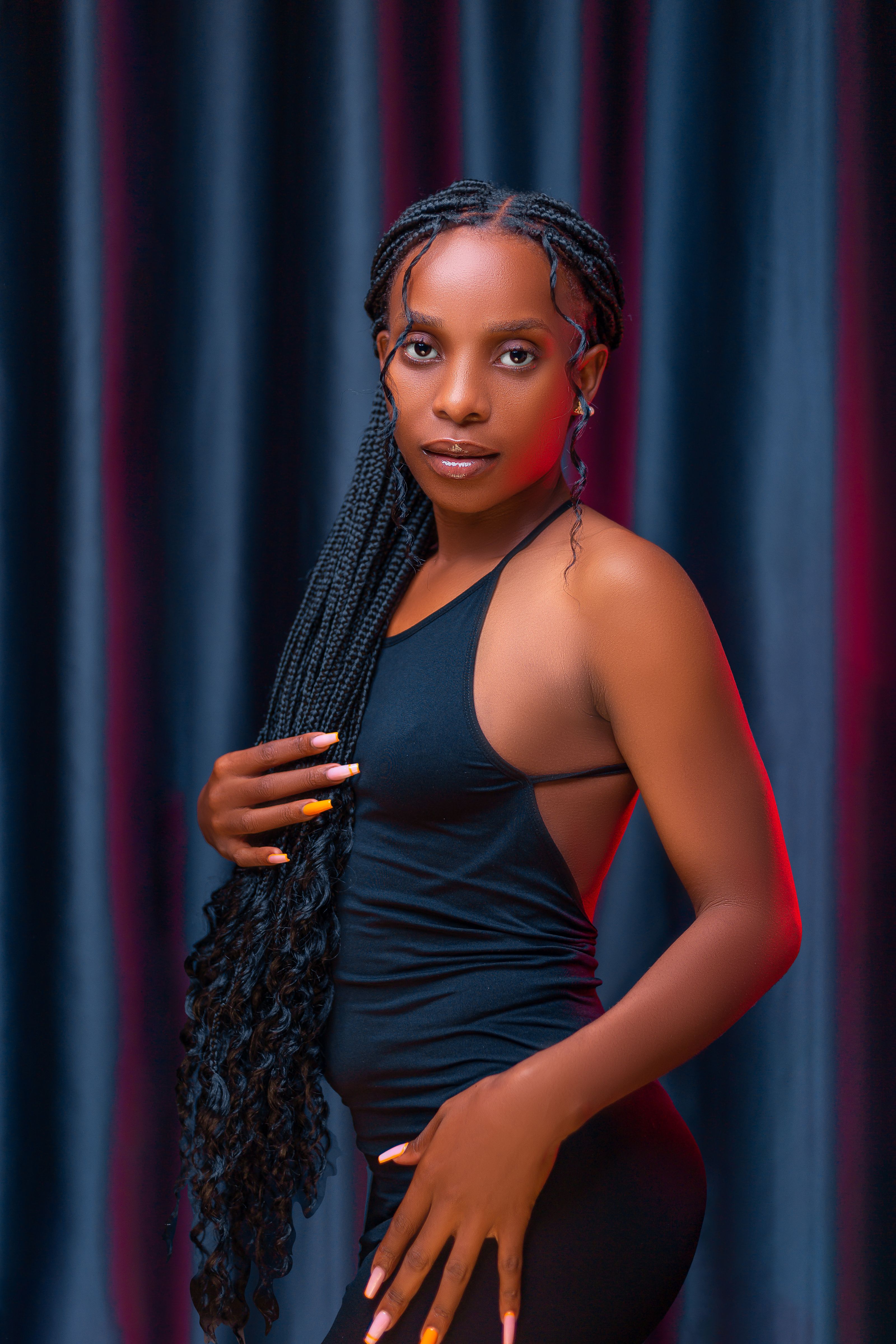 Uma mulher elegante posa com confiança em um vestido preto estiloso, exibindo seu cabelo trançado.
