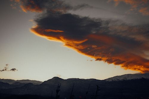 Free Captivating sunset with vibrant orange clouds over a mountainous landscape, creating a dramatic scene. Stock Photo