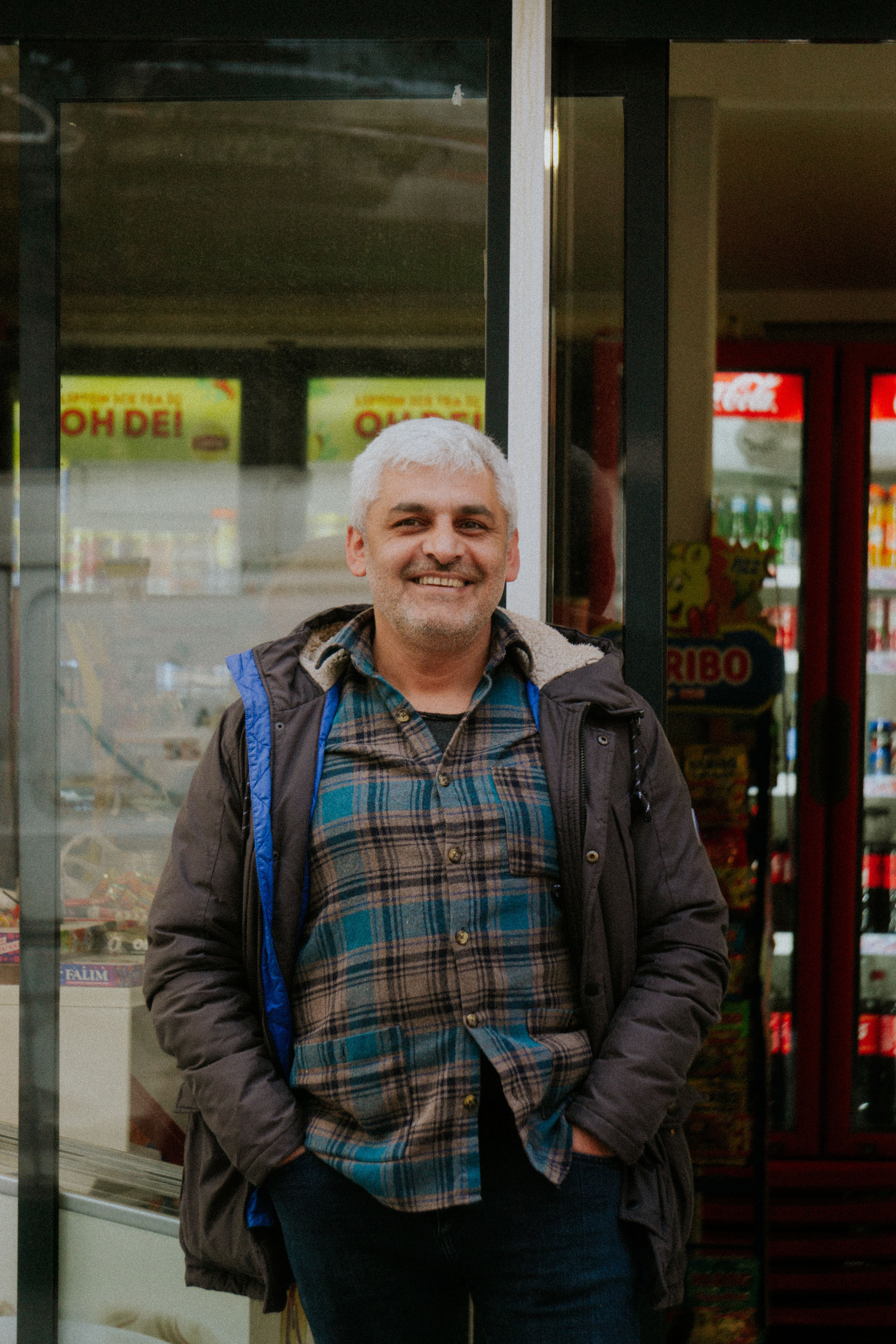 A middle-aged man smiling outside a storefront in Istanbul, showcasing local lifestyle with a welcoming demeanor.