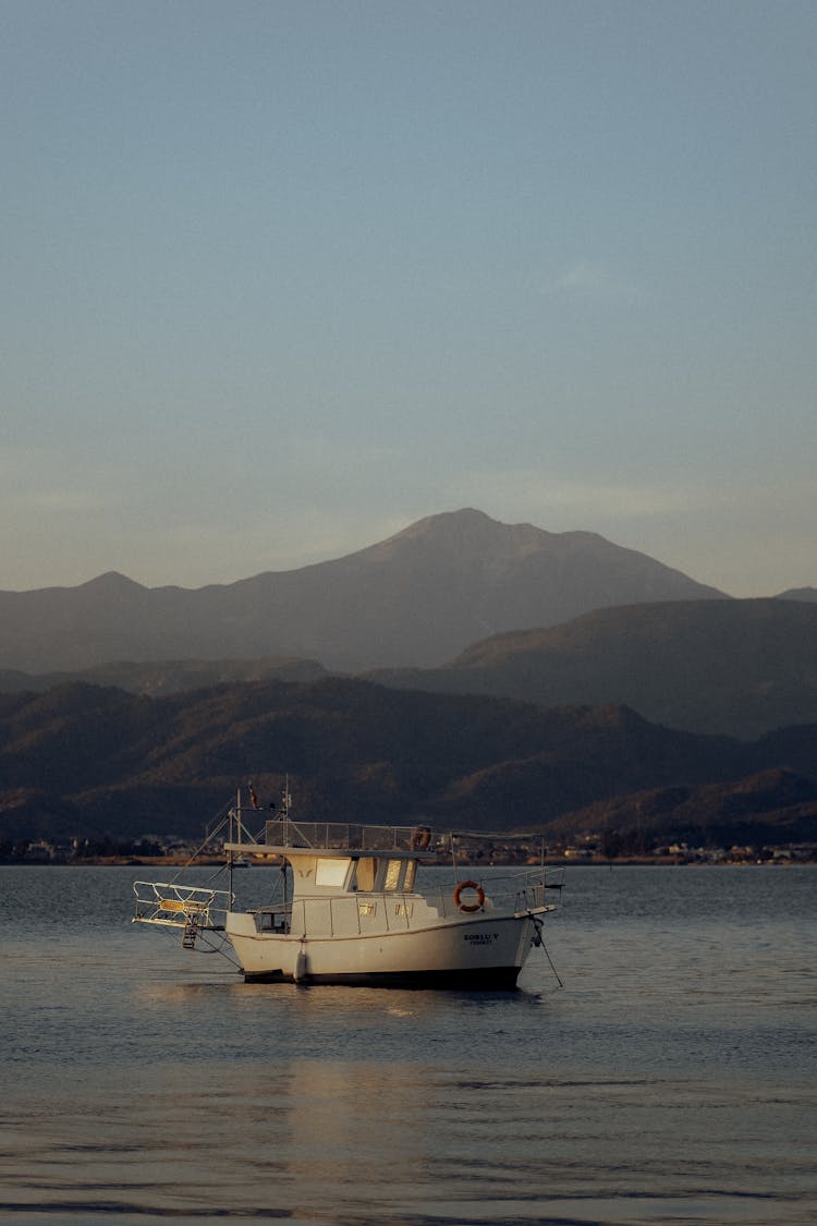 A Boat On The Water With The View Of Mountains In The Background 