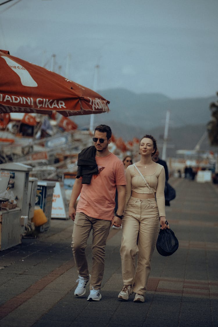 A Couple Walking Through The Market Near The Shore 