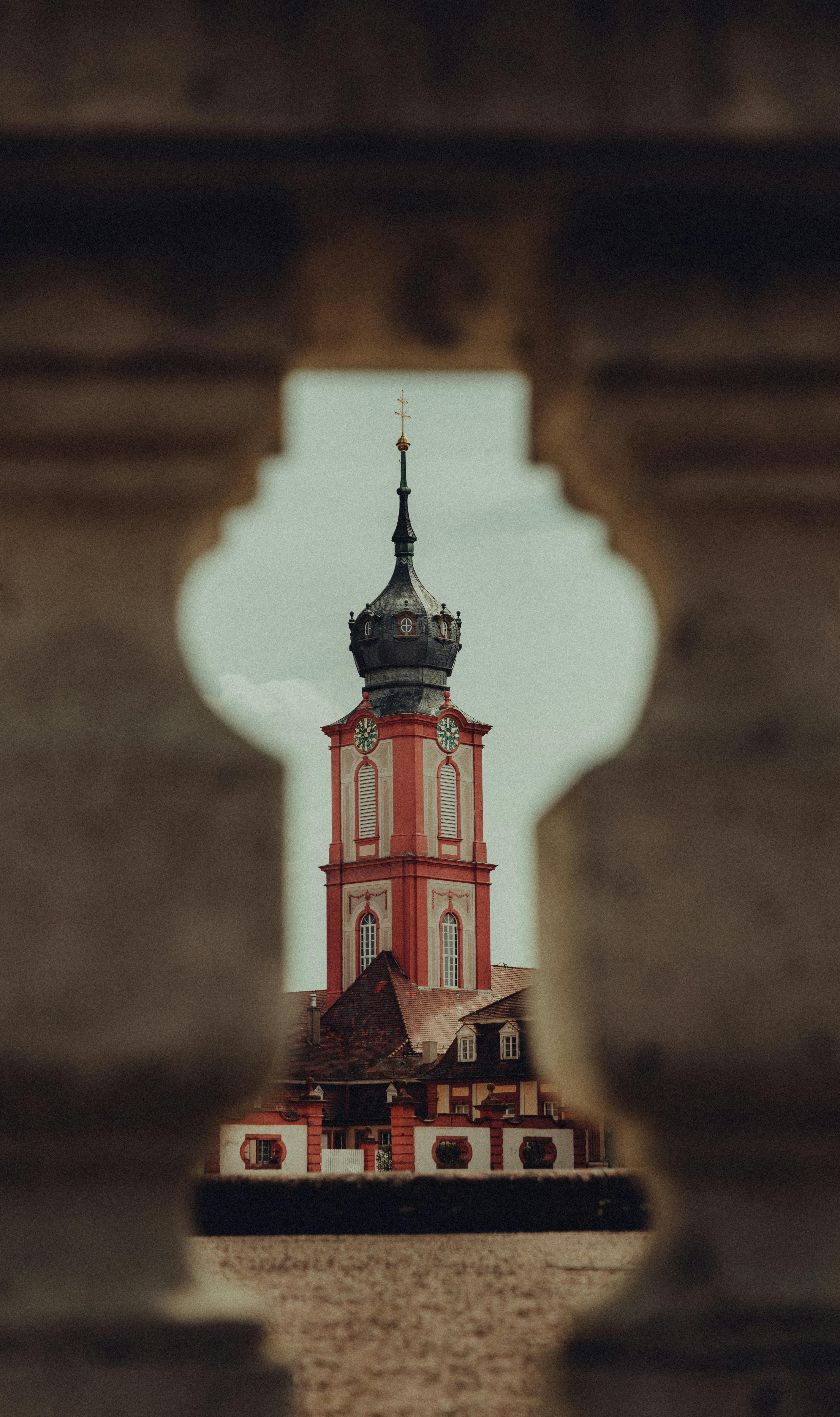 A striking view of the Baroque architecture at Bruchsal Castle, framed through an ornate stone railing.