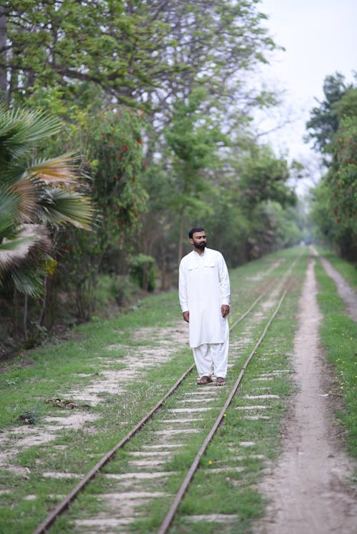 Man Standing in the Middle of Railway Tracks 