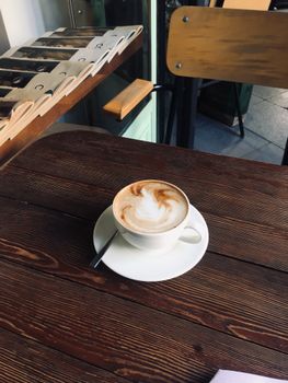 Cappuccino with frothy art in a cozy cafe setting. Perfect for coffee enthusiasts.