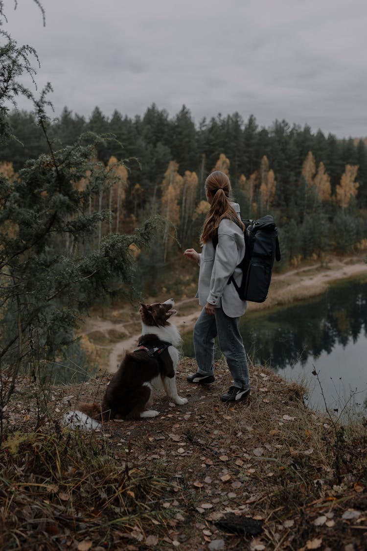 Woman Hiking With Her Dog By The Lake