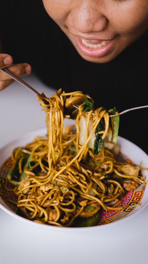Free Close-up of a person enjoying a traditional Indonesian noodle dish indoors. Vibrant and appetizing. Stock Photo