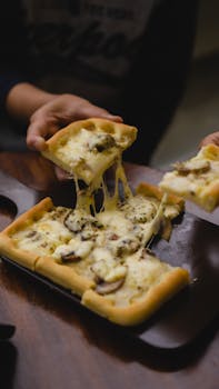Close-up of a mushroom and cheese pizza slice being served, showcasing its gooey texture.